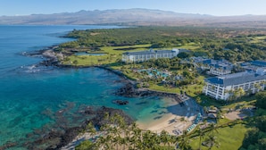 An aerial view of a resort with multiple buildings, a golf course, and a beach with clear waters. - Fairmont Orchid Gold Experience (Kamuela)