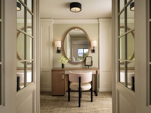 A hallway with a vanity, a mirror, two wall sconces, and a view of the outdoors. - Fairmont Orchid Gold Experience (Kamuela)