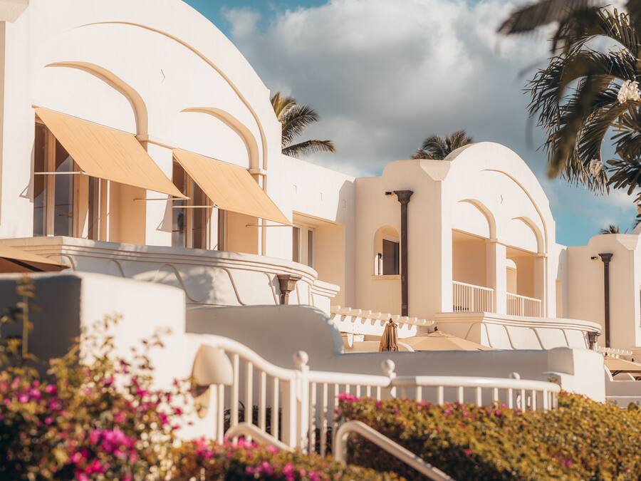 Un resort con edificios blancos, balcones y palmeras.