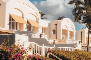 Un resort con edificios blancos, balcones y palmeras.