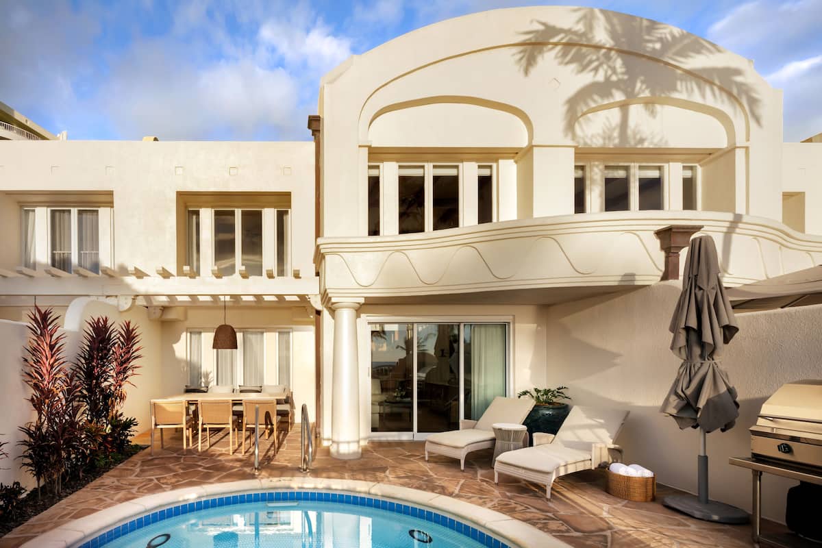 A modern house with a swimming pool, outdoor seating, and a covered patio area.