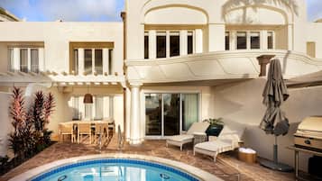 Une maison moderne dotée d’une piscine, d’un espace salon extérieur et d’un patio couvert.
