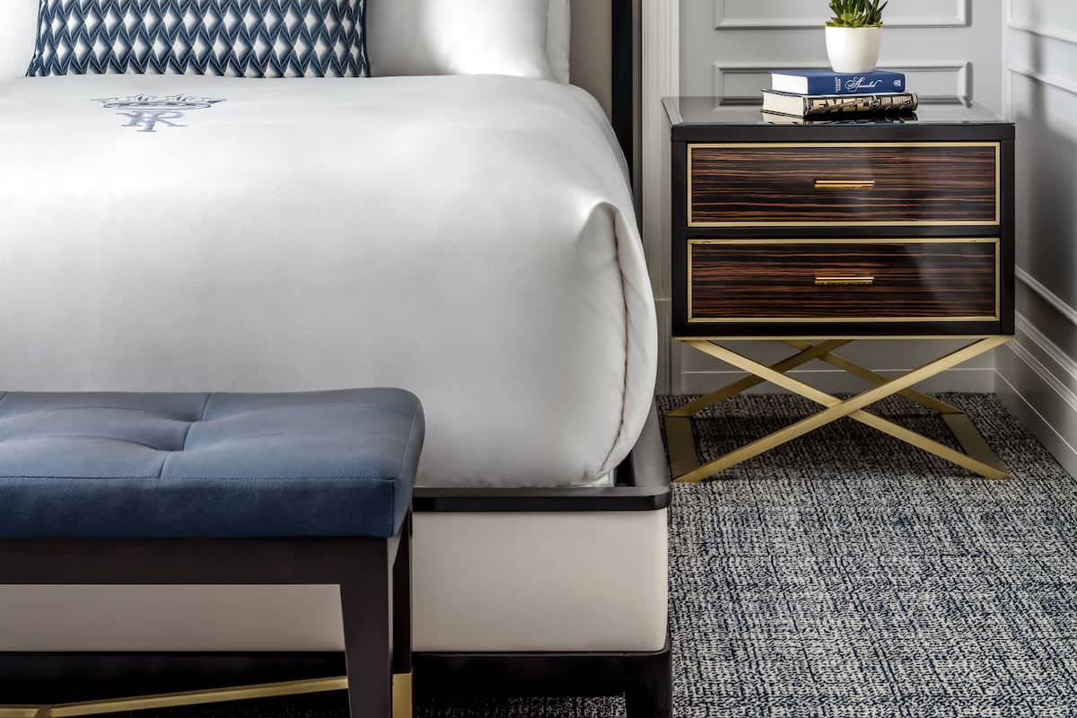 A modern bedroom with a large bed, a bedside table with a lamp, and a decorative wall panel.