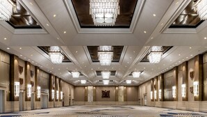 Una espaciosa y luminosa sala de conferencias con alfombra estampada, candelabros e iluminación empotrada.