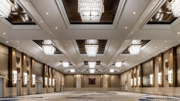 A spacious, well-lit conference room with a patterned carpet, chandeliers, and wall-mounted lights. - Fairmont Royal York Gold Experience (Toronto)