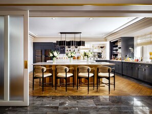A modern kitchen with a central island, bar stools, and a dining area.