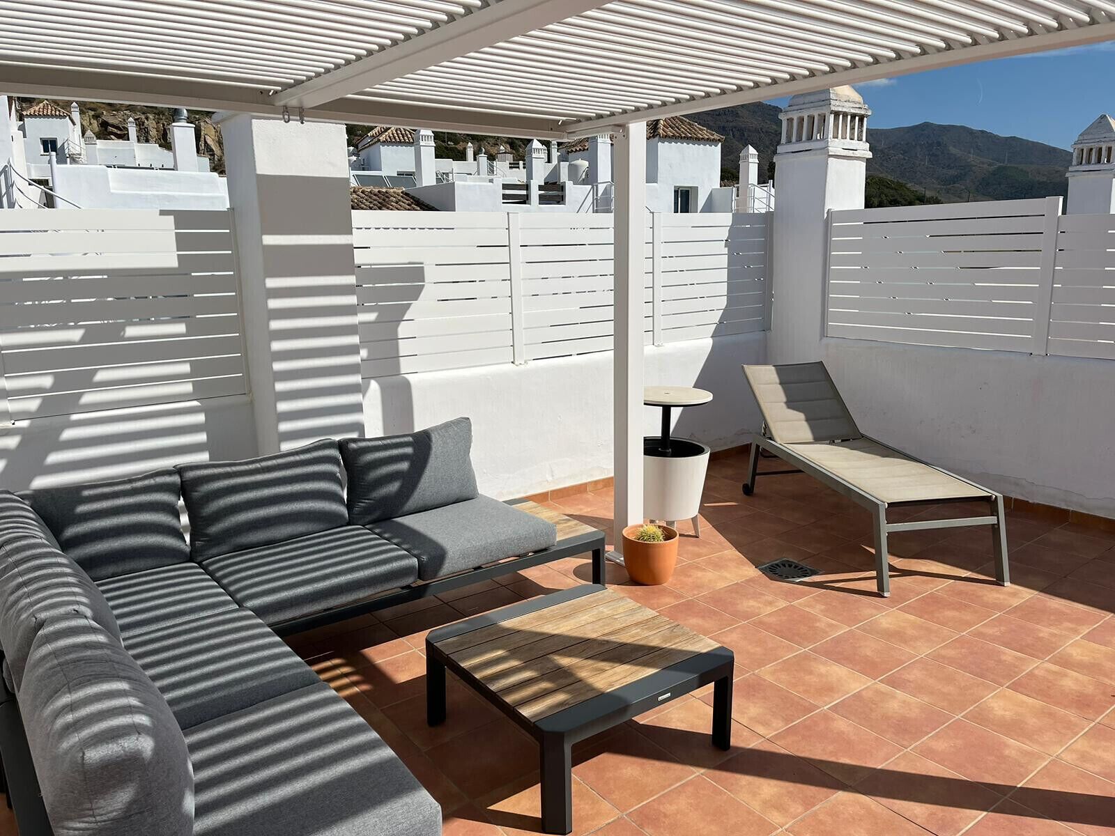 A rooftop terrace with a sofa, a table, and a chair.