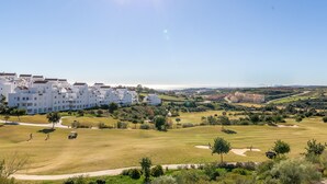 A golf course with a clubhouse, surrounded by white buildings with red roofs, and a clear sky. - Valle Romano Prestigious 2266 (Estepona)