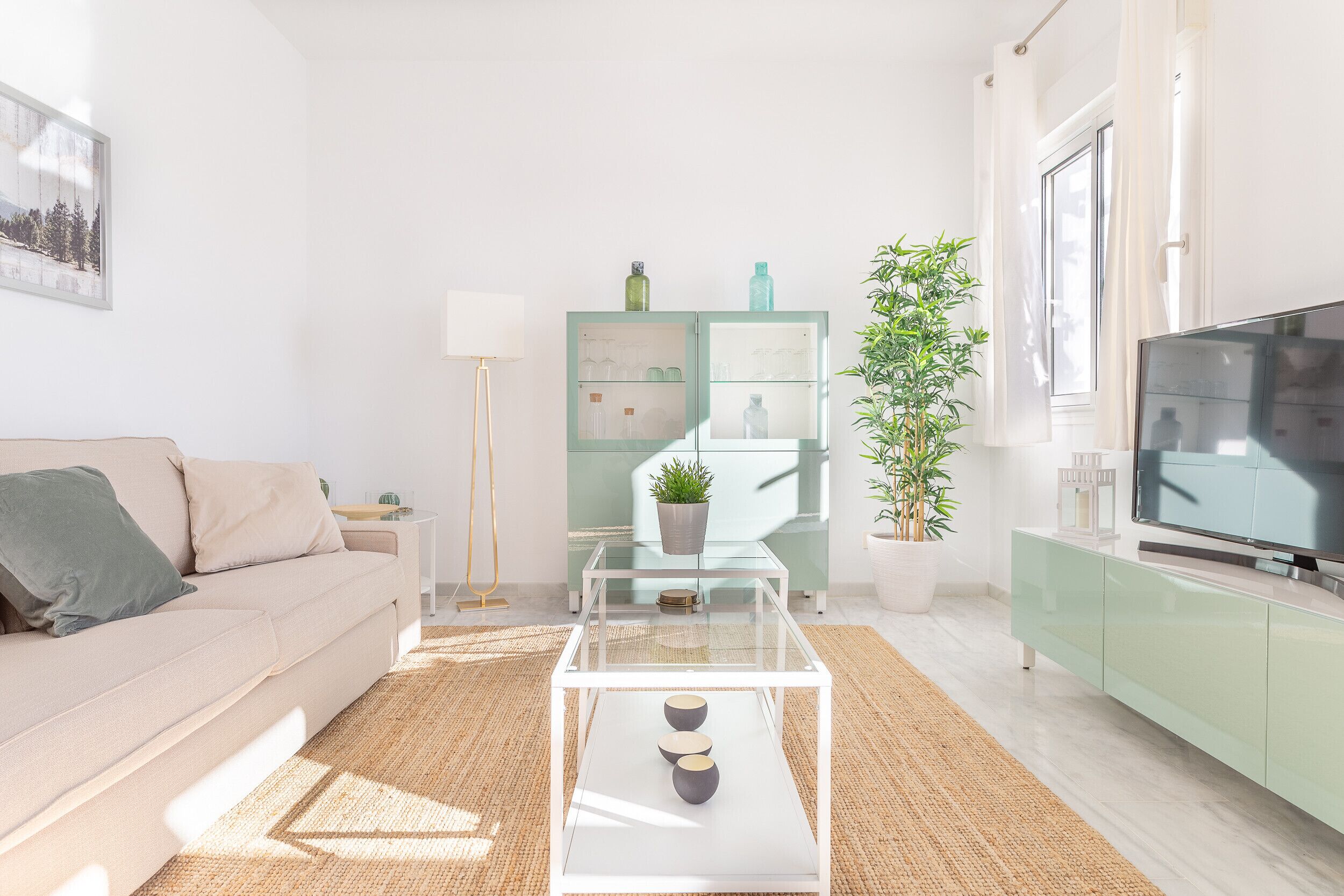 A modern living room with a sofa, a glass coffee table, a television, and a green cabinet.