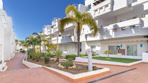 A residential building with a paved walkway, palm trees, and a well-maintained garden area. - Valle Romano Prestigious 2266 (Estepona)