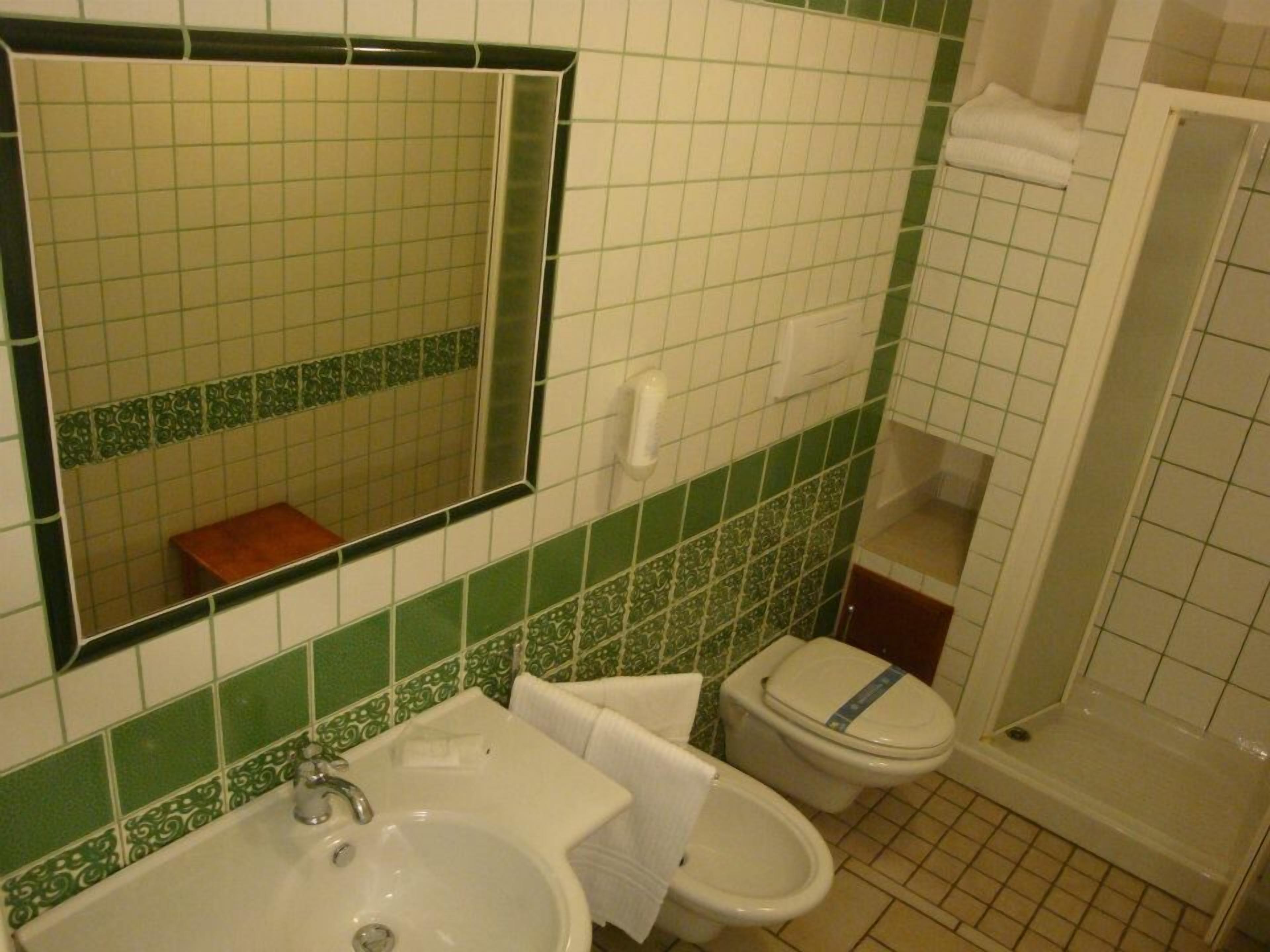 Un baño con lavamanos, espejo, inodoro y bidé.
