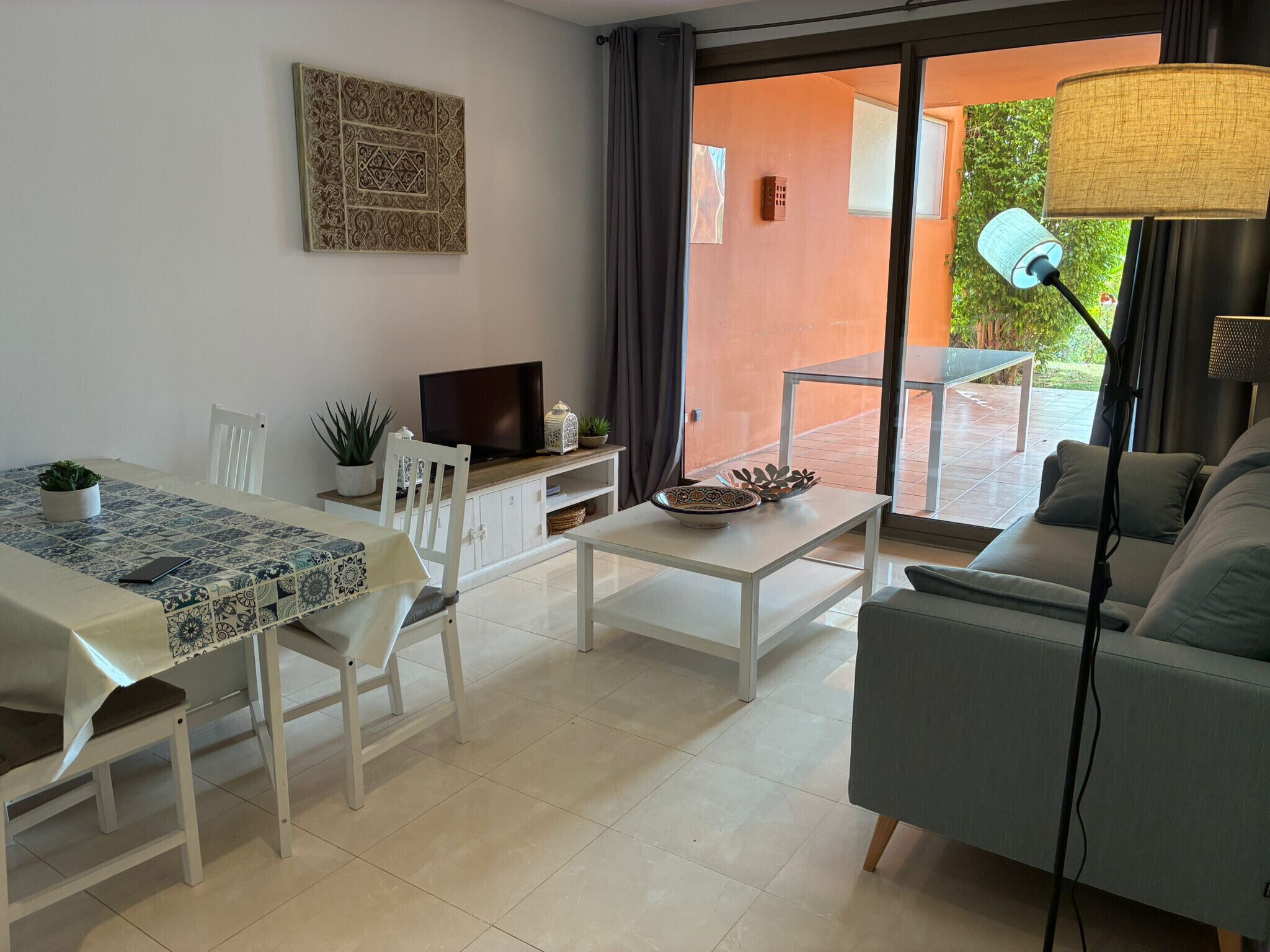 Una sala de estar moderna con sofá, mesa de comedor y televisor.