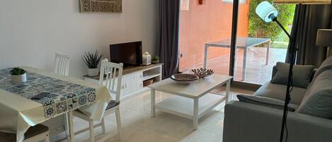 Una sala de estar moderna con sofá, mesa de comedor y televisor.