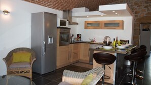 Eine kompakte Küche mit Kühlschrank, Mikrowelle, Ofen und einer Essecke mit Sitzgelegenheiten.