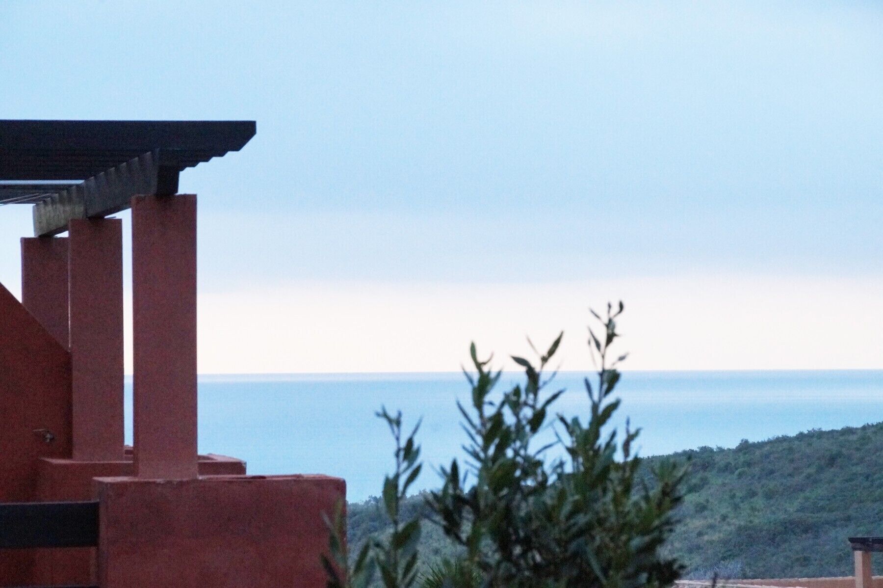 Ein Gebäude mit roter Fassade und Blick aufs Meer.
