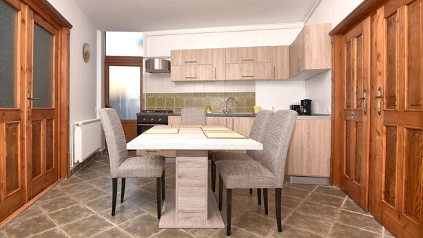 Una cucina con mobili in legno, pavimento piastrellato e un tavolo da pranzo con sedie.