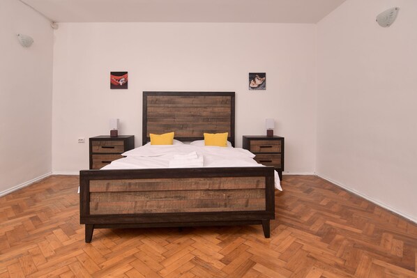 Une chambre à coucher avec un lit en bois, deux tables de chevet et deux lampes fixées au mur.