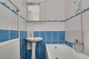 A bathroom with a white bathtub, a white sink, and a mirror above the sink.