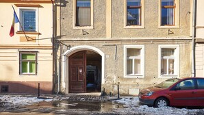 Un edificio con un'ampia entrata ad arco, diverse finestre e un'auto rossa parcheggiata davanti.