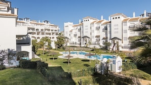 Een resort met witte gebouwen, een zwembad en palmbomen.