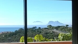 A view from a window overlooking a coastal landscape with a mountain in the distance.
