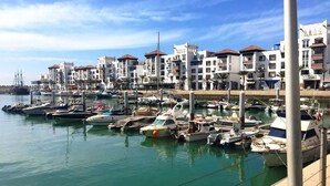 Un port de plaisance où sont amarrés de nombreux bateaux, entouré de bâtiments blancs aux toits rouges.