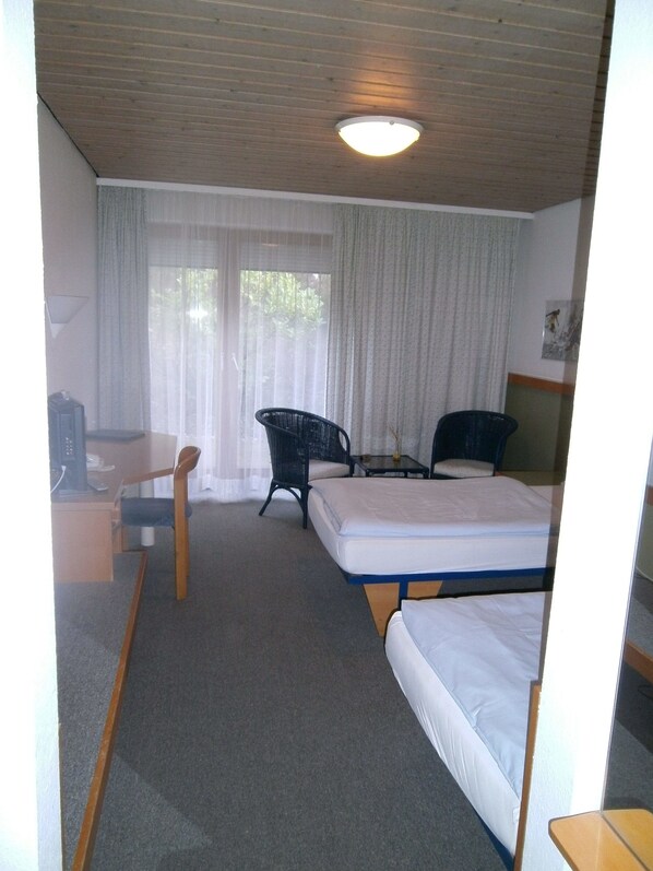 A hotel room with a bed, a desk, a chair, and a small table.