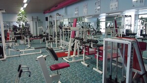 A gym with various exercise equipment, mirrors, and a patterned carpet.