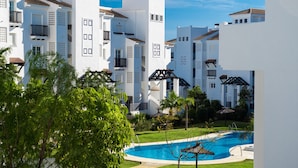 Un resort con edificios blancos, piscina y abundante vegetación.