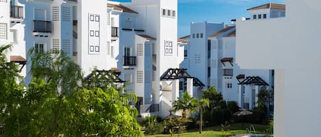 A resort with white buildings, a swimming pool, and lush greenery.