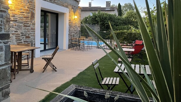 Un bâtiment en pierre doté d’une piscine, d’un espace extérieur aménagé et d’une pelouse bien entretenue.