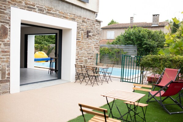 A patio with a pool, outdoor seating, and a stone wall.