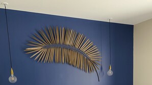Une chambre avec un grand lit, du linge de lit blanc, un mur d’accent bleu et un élément décoratif mural.
