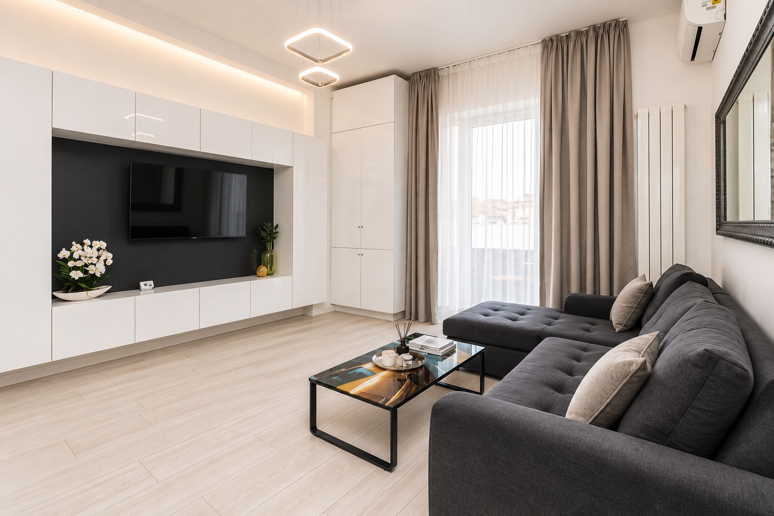 Ein modernes Wohnzimmer mit Flachbildfernseher, einer Couch, einem Couchtisch und einem großen Fenster mit Vorhängen.