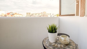 A balcony with a potted plant and a mosaic table. - Metropole Apartments Old Town (Bucharest)