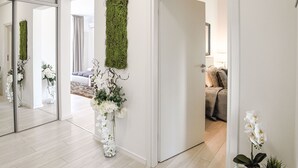 A modern interior with a hallway leading to a bedroom. There are decorative plants and a red vase on a shelf. - Metropole Apartments Old Town (Bucharest)