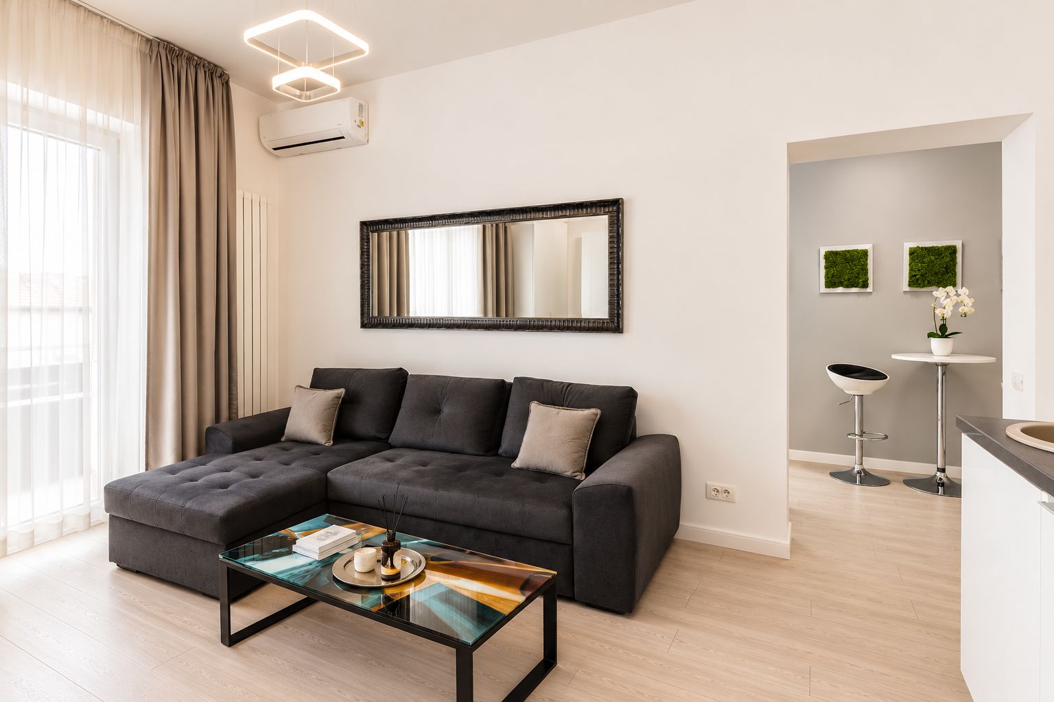 A modern living room with a sectional sofa, a glass coffee table, and a large mirror on the wall.
