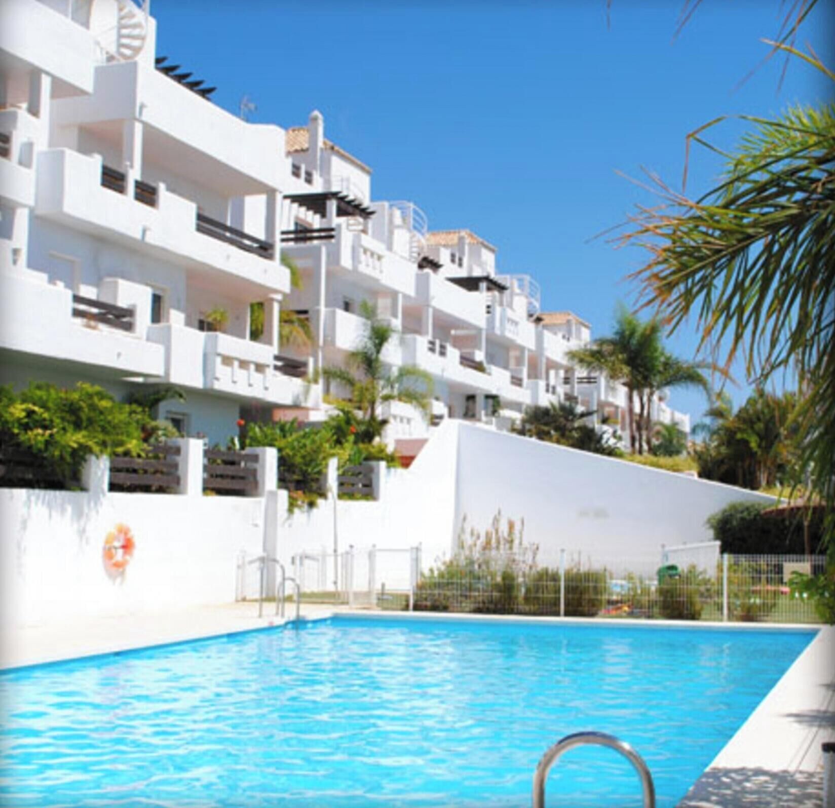 Um edifício moderno com várias varandas e uma piscina.