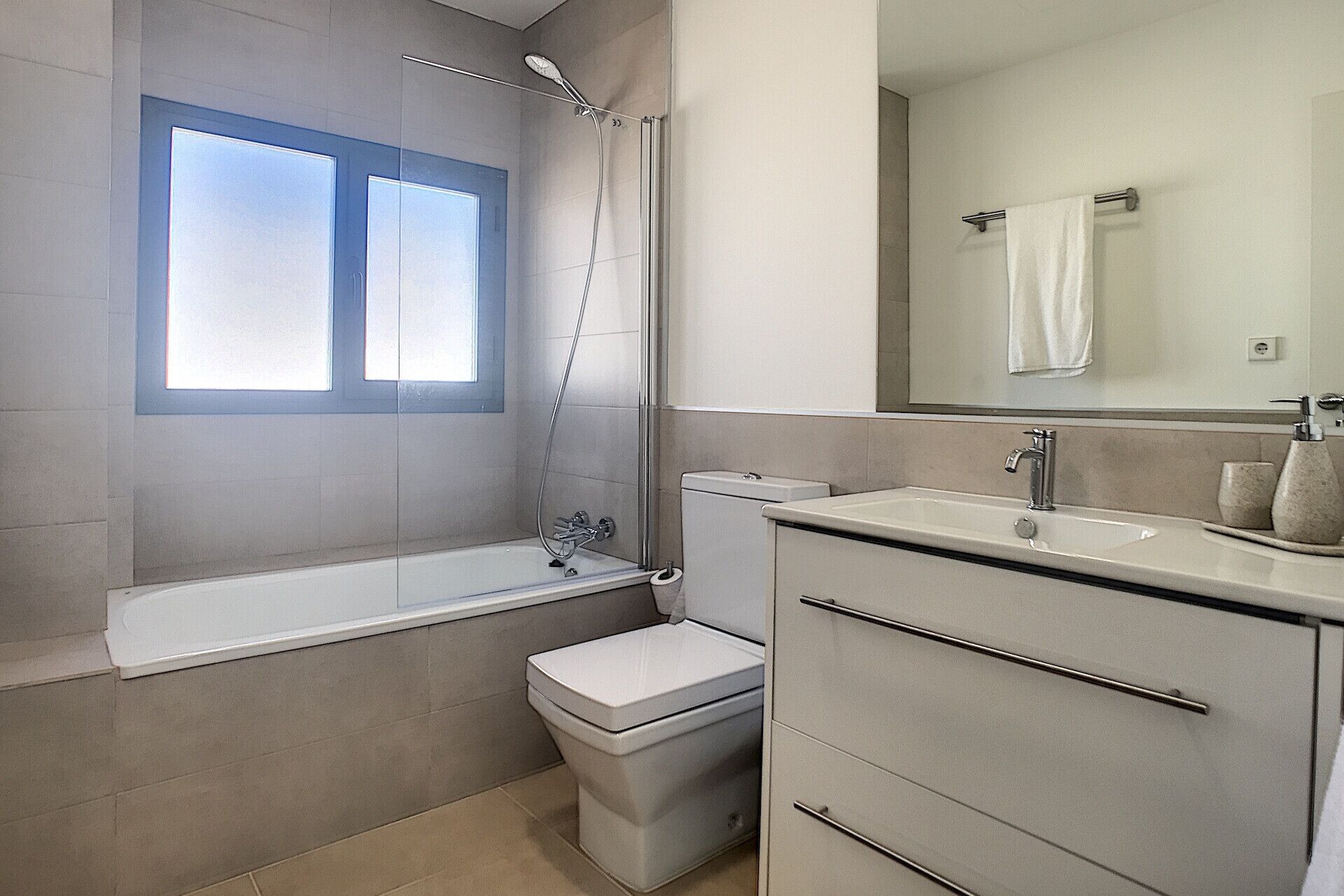 Une salle de bain moderne équipée d’une baignoire, de toilettes et d’un meuble-lavabo avec un miroir.