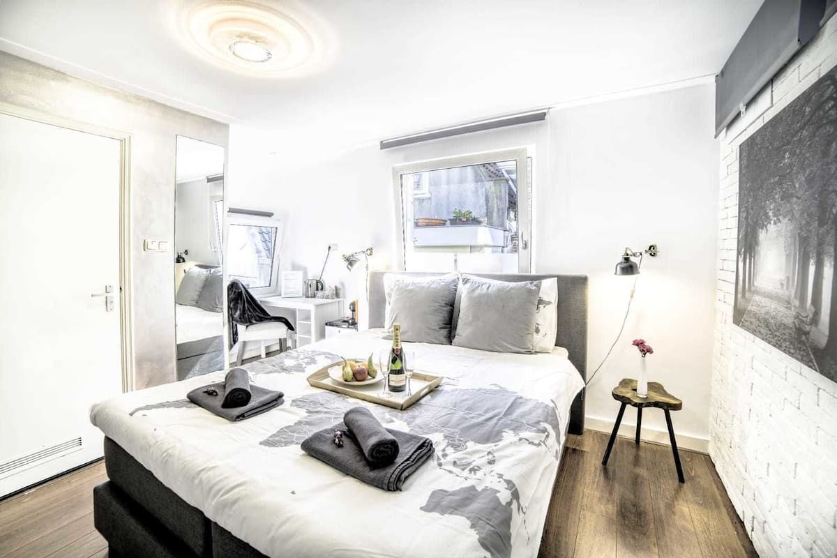 A modern bedroom with a large bed, a desk, and a window.