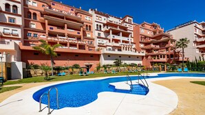 Un hôtel doté de nombreux balcons, d’une piscine et de chaises longues.