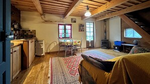 Un acogedor dormitorio en ático con vigas de madera, zona de comedor, sofá, alfombra y chimenea.