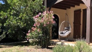 A house with a porch, a hanging chair, and a garden with various plants.