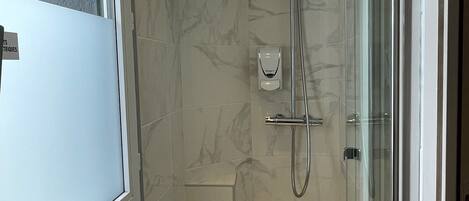 Un baño moderno con cabina de ducha de vidrio, un lavabo con espejo y un inodoro.