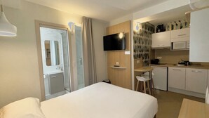 A hotel room with a bed, a TV, a kitchenette, and a bathroom with a shower and toilet. - Kyriad Direct Saint Brieuc - Parc des Expositions (Tregueux)