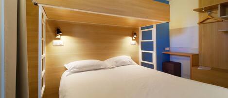 A bedroom with a bed, bedside lamps, a wardrobe, and a desk.