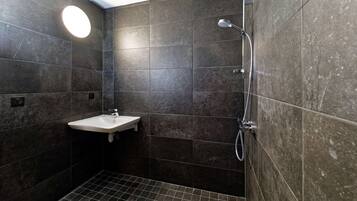 A bathroom with dark tiles, a white sink, and a shower.