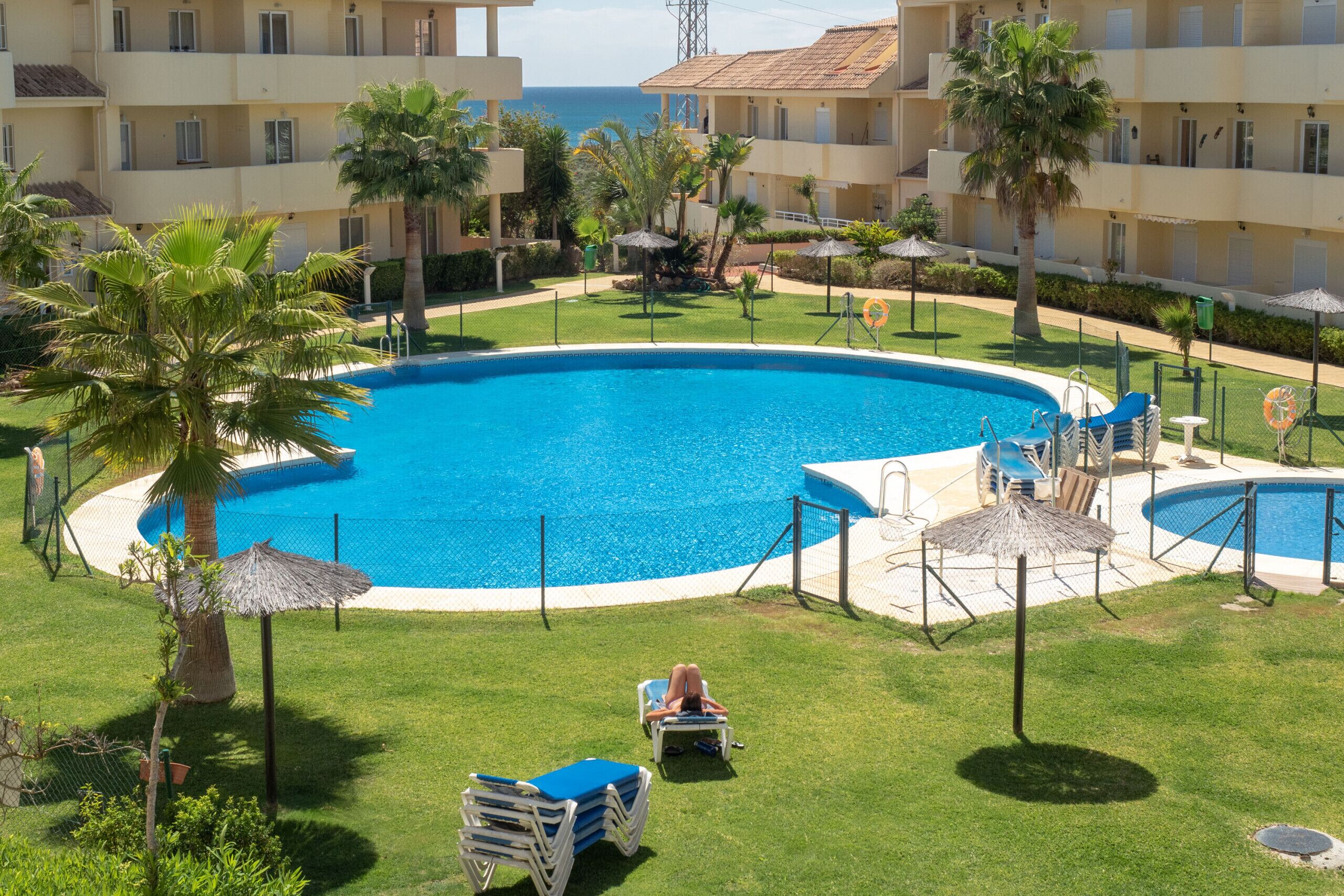 A resort with a large pool surrounded by palm trees and lounge chairs.