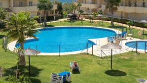 Un resort con una piscina grande rodeada de palmeras y sillas de descanso.