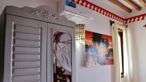 Ein Zimmer mit grauem Kleiderschrank, einem Sonnenuntergangsbild und einem Deckenventilator.